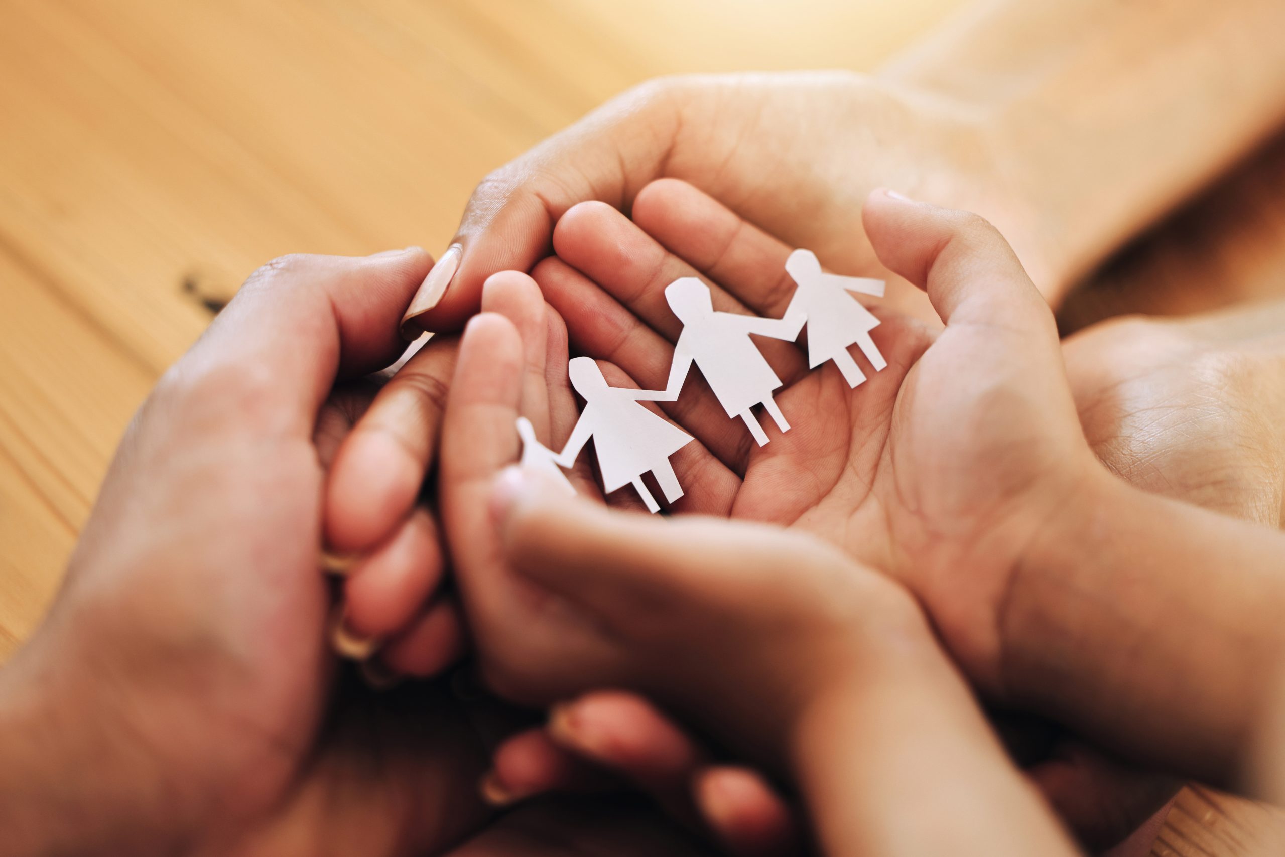 Hands holding a paper-cutout family